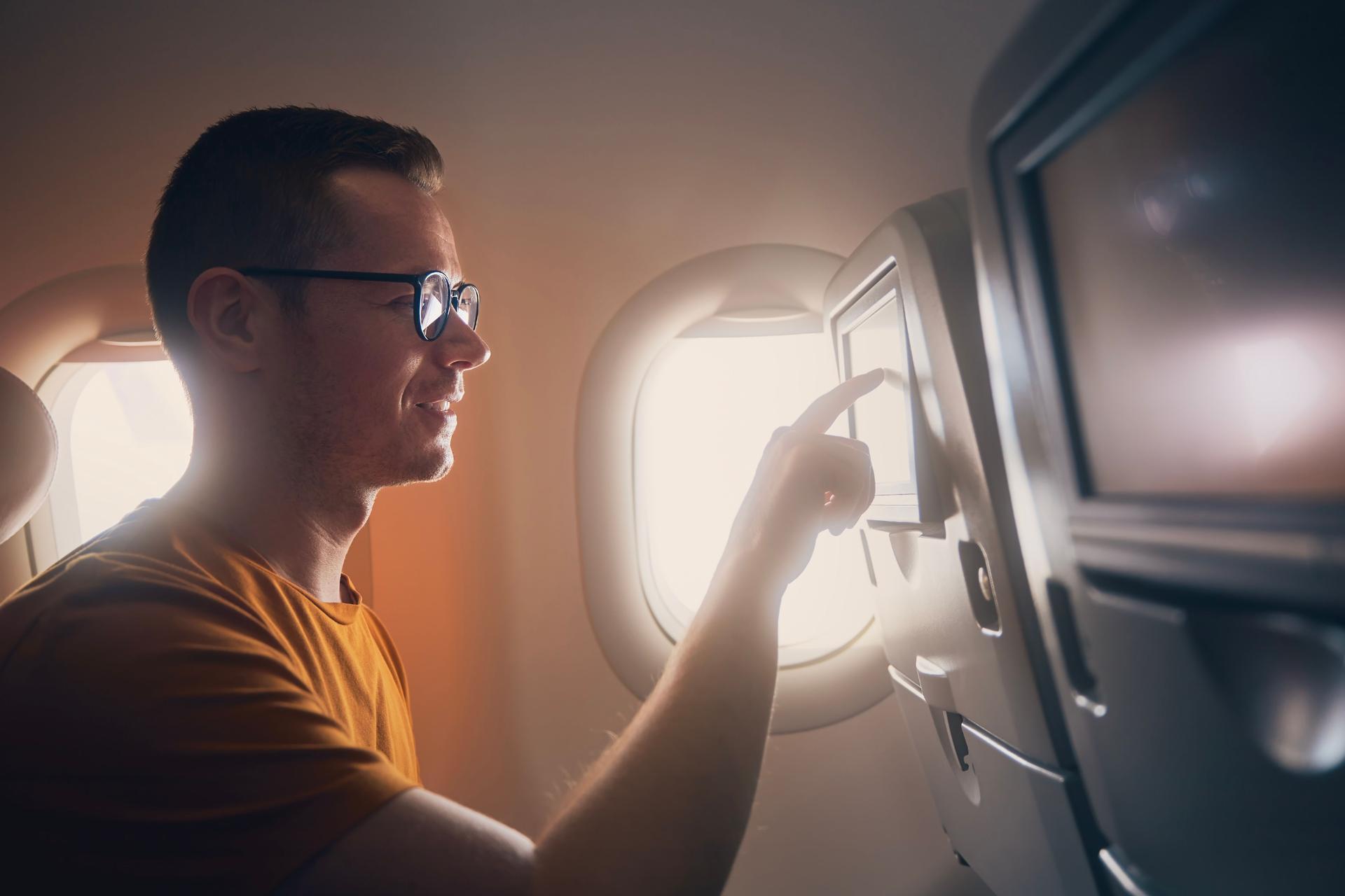 Happy passenger while using in-flight entertainment system during flight